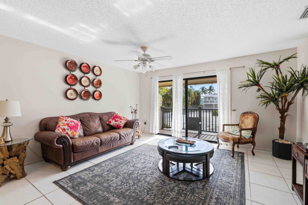 Living room with a leather sofa, round coffee table, and sliding glass doors opening to the balcony