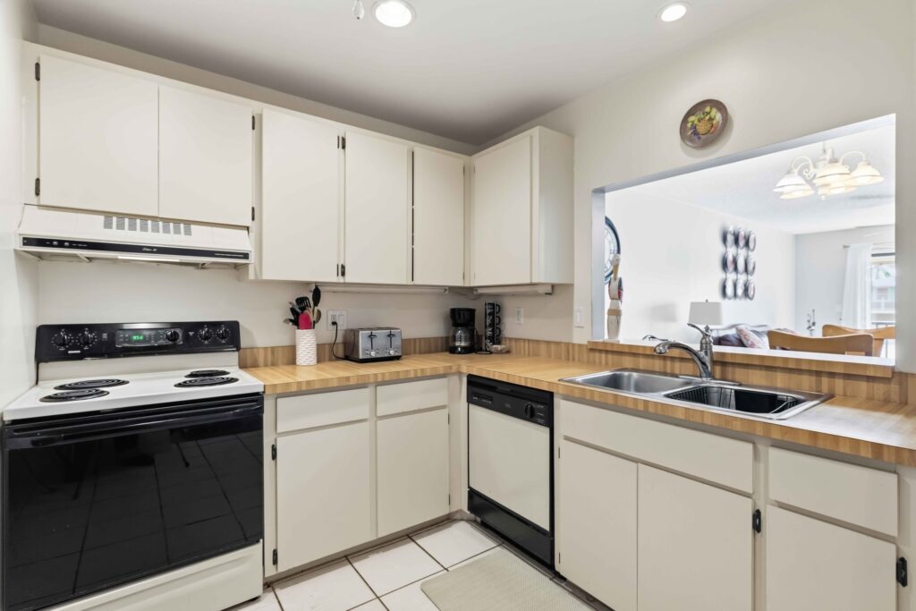 Kitchen with white cabinetry, wood-grain design laminate countertops, and stainless steel sink